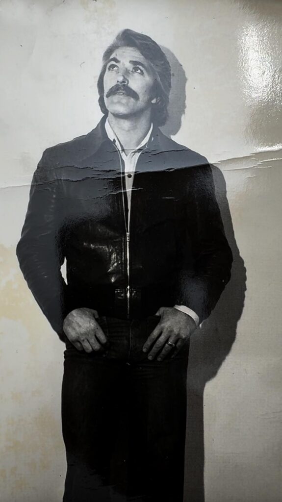 Fotografia in bianco e nero degli anni 70 con un uomo in piedi che posa per una foto 