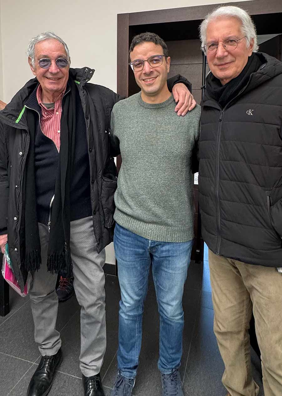 Tre uomini in piedi in posa per una foto sorridono di fronte all'obiettivo